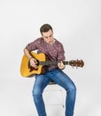 Teenage guitar player sits on a chair and plays western guitar Royalty Free Stock Photo