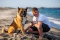 Teenage guy with blond hair and leash in hands plays and walks with dog of Akina Inu breed on wild beach along Black Sea Royalty Free Stock Photo