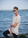 Teenage guy relaxing near the river. A casual boy outdoors on a blurred background. Modern fashion concept. Copy space.