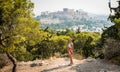 Teenage jogger in red shirts stretching in front of the Acropolis and Parthenon