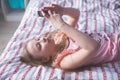 Teenage lying on her back bed and looks in phone