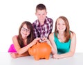 Teenage putting coins into big piggy bank