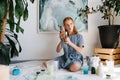 Teenage redhead girl is grimacing, holding bunch of brushes in hands Royalty Free Stock Photo