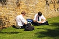 Teenage schoolboys sittin on grass working.