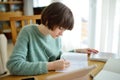 Teenage schoolgirl doing her homework with digital tablet at home. Child using gadgets to study. Education and distance learning Royalty Free Stock Photo