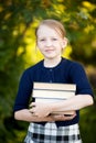 Teenage schoolgirl holding pile of books and smiling. Royalty Free Stock Photo