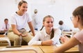 Teenage schoolgirls friendly talking during recess in classroom Royalty Free Stock Photo