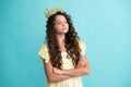 Teenage selfish girl celebrates success victory. Teen child in queen crown isolated on blue background. Princess girl in