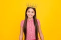 Teenage selfish girl celebrates success victory. Teen child in queen crown isolated on yellow background. Princess girl