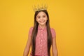 Teenage selfish girl celebrates success victory. Teen child in queen crown isolated on yellow background. Princess girl