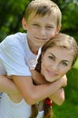 Teenage sister and little brother happy smiling & looking at camera embracing outdoors