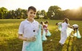 Teenage smiling boy with trash bag collecting plastic garbage in the summer park. Royalty Free Stock Photo