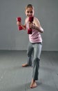 Teenage sportive girl is doing exercises with dumbbells to develop with dumbbells muscles on grey background. Sport healthy
