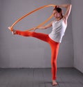 Teenage sportive girl is doing exercises with hula hoop t on grey background. Having fun playing game . Sport healthy lifestyle co