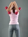 Teenage sportive girl is doing exercises to develop with dumbbells muscles on grey background. Sport healthy lifestyle concept. Sp