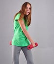 Teenage sportive girl is doing exercises to develop muscles on grey background. Sport healthy lifestyle concept. Sporty