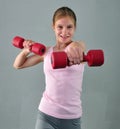 Teenage sportive girl is doing exercises to develop muscles on grey background. Sport healthy lifestyle concept. Sporty