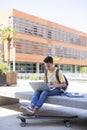 Teenage student boy using laptop computer outside high school