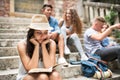 Teenage student girl sitting on stone steps reading a book. Royalty Free Stock Photo