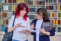 Teenage student girl talking to female teacher mentor in the library. Royalty Free Stock Photo