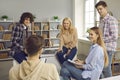 Teenage student group having friendly talk during rest on break in classroom