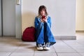 Teenage student in headphones with backpack smartphone sitting on floor near wall. Royalty Free Stock Photo