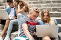 Teenage students with laptops sitting on stone steps. Royalty Free Stock Photo