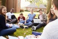 Teenage Students Sitting Outdoors And Working On Project