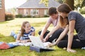 Teenage Students Sitting Outdoors And Working On Project