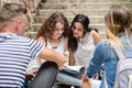 Teenage students sitting on stone steps in front of university. Royalty Free Stock Photo