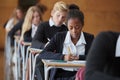 Teenage Students In Uniform Sitting Examination In School Hall