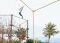 Teenage teen girl bungee flying in rope amusement park. Climbing harness equipment, green sports safety helmet