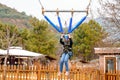 Teenage teen girl bungee flying in rope amusement park. Climbing harness equipment, green sports safety helmet