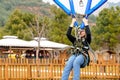 Teenage teen girl bungee flying in rope amusement park. Climbing harness equipment, green sports safety helmet