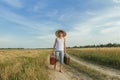 Teenage traveler with old suitcase on country road