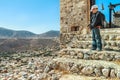 Teenage traveler standing high up on stone steps of ancient Byzantine Castle of Chora on Greek Kalymnos island