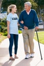 Teenage Volunteer Helping Senior Man ToWalk