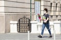 Teenage woman wearing face mask walking city street on a sunny day while holding a rose bouquet