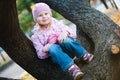 Teenaged girl sitting with teddy bear on tree - purple dots jacket.