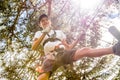 Teenager with action camera having fun on high ropes course, adventure park, climbing trees in forest Royalty Free Stock Photo