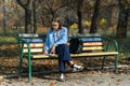 A teenager on a bench is doing homework on a sunny autumn day. Royalty Free Stock Photo