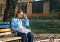 A teenager on a bench is doing homework on a sunny autumn day. Royalty Free Stock Photo