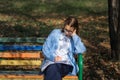 A teenager on a bench is doing homework on a sunny autumn day. Royalty Free Stock Photo