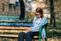 A teenager on a bench is doing homework on a sunny autumn day. Royalty Free Stock Photo