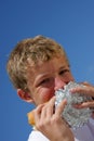 A teenager biting into a sandwich