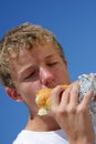 A teenager biting into a sandwich with closed eyes