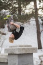 Teenager blonde hair man training parkour jump in the snow covered park