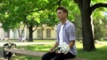 Teenager with bouquet of flowers sits on bench in park, waiting for girlfriend