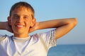 Teenager boy against sea, hands behind head Royalty Free Stock Photo