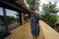 Teenager boy in bath robe stand in wooden terrace of modern house Royalty Free Stock Photo